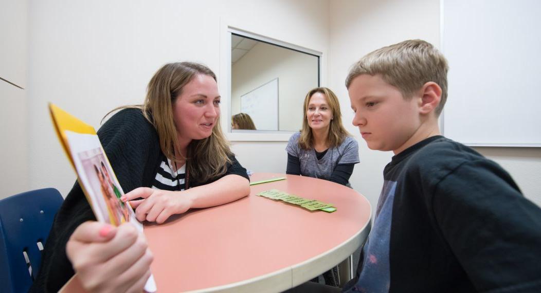 a child works with a speech-language pathologist student in a clinical setting
